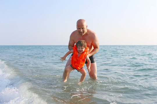 father teaching his 2 years son to swim in sea