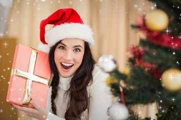 Composite image of surprised brunette holding a gift