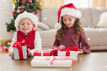 Fototapeta na wymiar Composite image of festive siblings smiling at their gifts