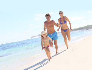 Family running in swimsuit on a Caribbean beach