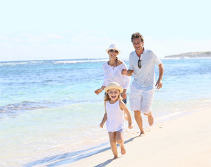 Family running on a white sandy beach