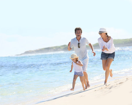 Couple with little girl running on Caribbean beach