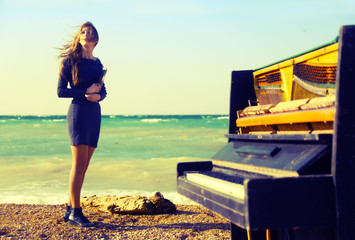 beautiful girl with notes from an old piano on the beach