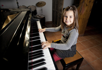 Happy eight year old girl playing the piano