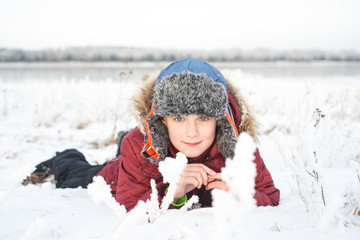 Portrait of little happy boy lies in snow