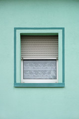 Einfaches PVC Fenster mit Rollladen in grüner Fassade