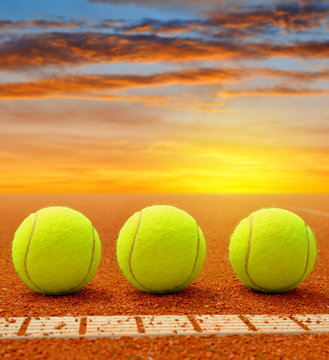 Tennis balls on a tennis clay court in the sunset