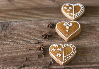 Gingerbread hearts with spices on wooden background