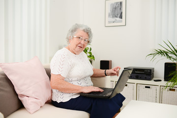 cheerful elderly woman websurfing and shopping internet laptop