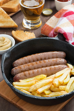 grilled sausages with French fries, toast and beer, close-up
