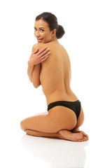 Fototapeta premium Nude woman sitting on knees embracing herself