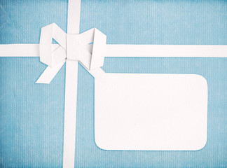 Gift ribbon and bow with blank gift tag, blue retro background