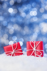 Two red gift boxes in snow on abstract background