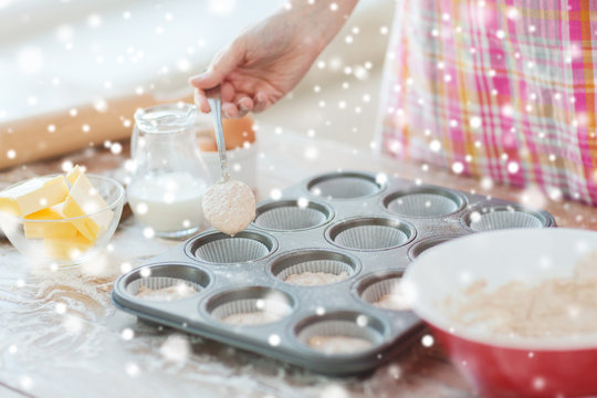 close up of woman filling muffins molds with dough