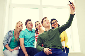 five smiling students taking picture with camera