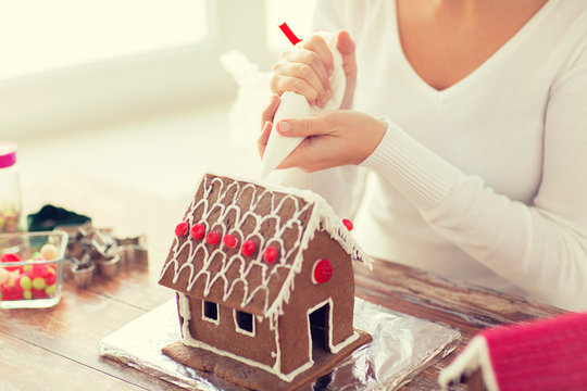 close up of woman making gingerbread house at home