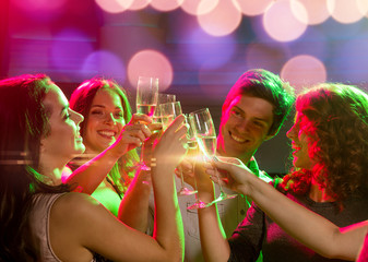 smiling friends with glasses of champagne in club