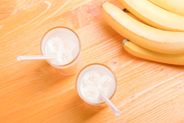 two glasses of banana juice on the table next to a yellow ripe b