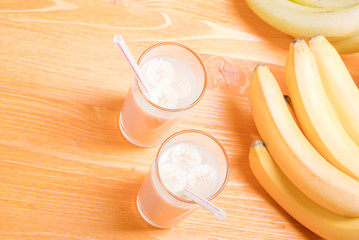 two glasses of banana juice on the table next to a yellow ripe b