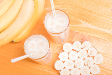 two glasses of banana juice on the table next to a yellow ripe b