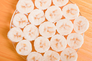 peeled and sliced banana slices on a glass plate on a yellow tab