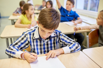 group of school kids writing test in classroom