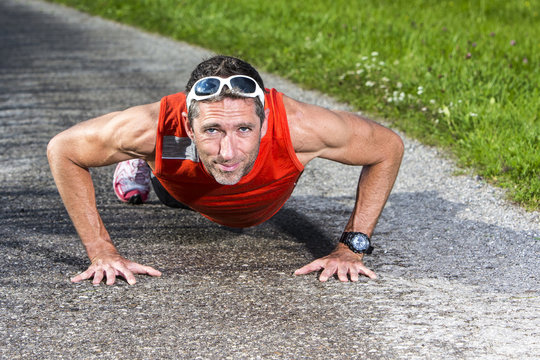 Sportlicher Mann macht Liegestütze im Freien - Powered by Adobe
