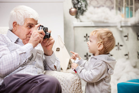 Senior man taking photo of his grandson at Christmas time