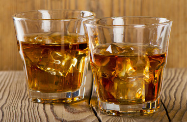 Glasses of whiskey on wooden background