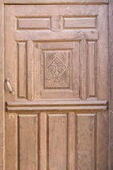 Old brown run-down religious decorated wooden door