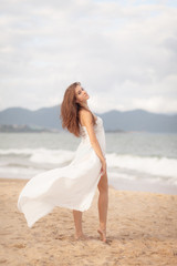 Fototapeta na wymiar Beautiful Girl With White Scarf on The Beach. Travel and Vacation. Freedom Concept