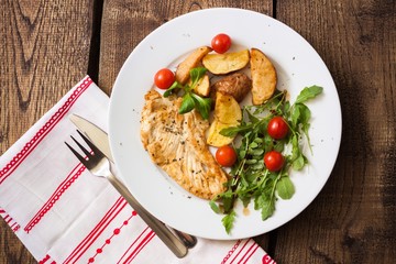 Slices of grilled chicken steak with potatoes and vegetables