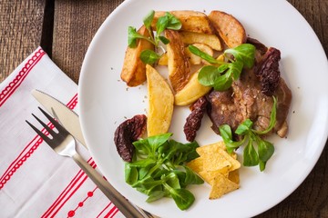 Slices of roasted pork meat with dried potatoes and lettuce