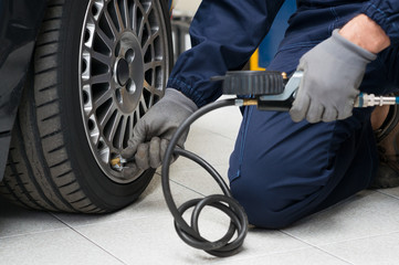 Fototapeta na wymiar Mechanic Checking Tyre Pressure With Gauge
