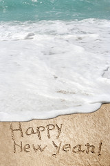 Conceptual Happy New Year text in sand and water