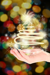 Christmas concept. Female hand with lights in shape of fir tree