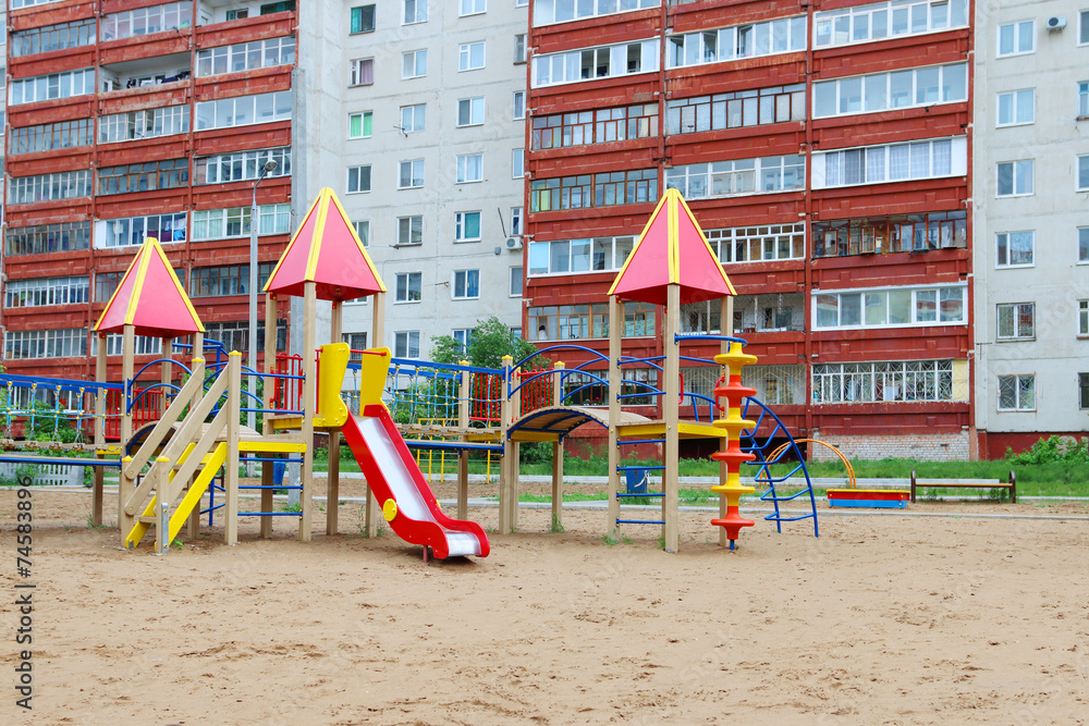 Wall mural colorful playground in sand next to high-rise residential buildi