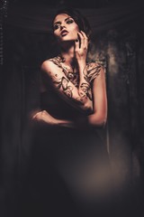 Tattooed beautiful woman in old spooky interior