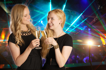 Freundinnen mit Sektgläsern vor Disco-Hintergrund