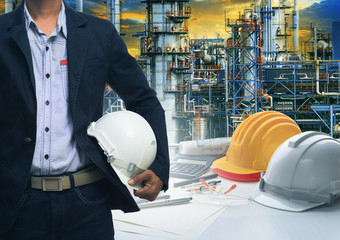 engineering man standing with white safety helmet against  oil r