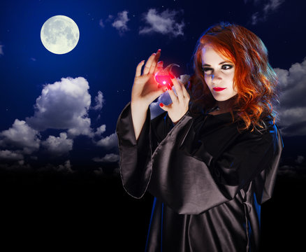 Witch with potion on night sky background