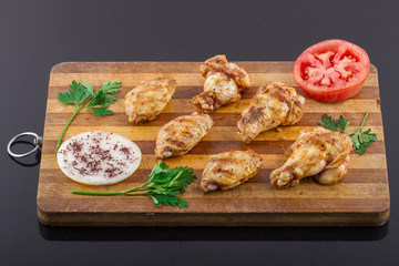 grilled chicken wings and legs on wooden plate