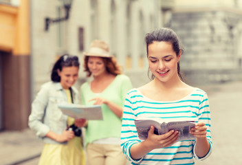 smiling teenage girls with city guides and camera