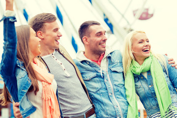 group of smiling friends in amusement park