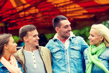 group of smiling friends in amusement park