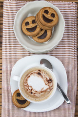 Cup of cafe au lait with smiling cookies