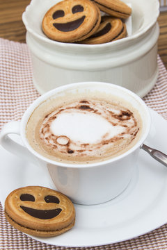 Cup of cafe au lait with smiling cookies