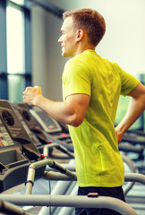 Fototapeta na wymiar smiling man exercising on treadmill in gym