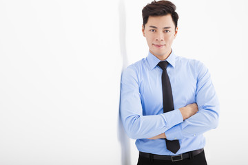young businessman leaning against white wall in office