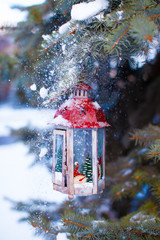 Decorative Christmas lantern on fir branch in snow winter day